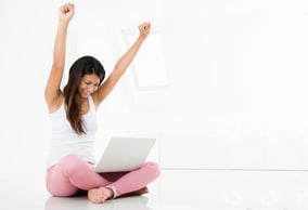 Successful woman winning online celebrating with arms up